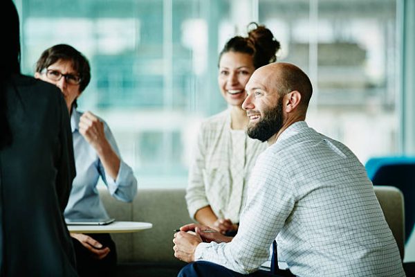 Smiling businessman in discussion with colleagues during informal project meeting in office