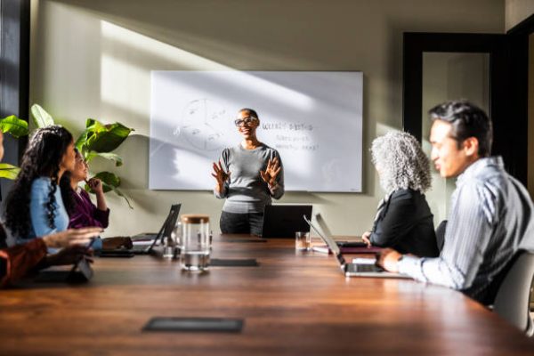 Female business owner speaking to office workers in modern conference room